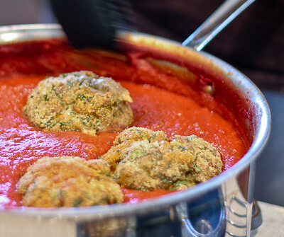 Giant meatballs simmering in marinara sauce