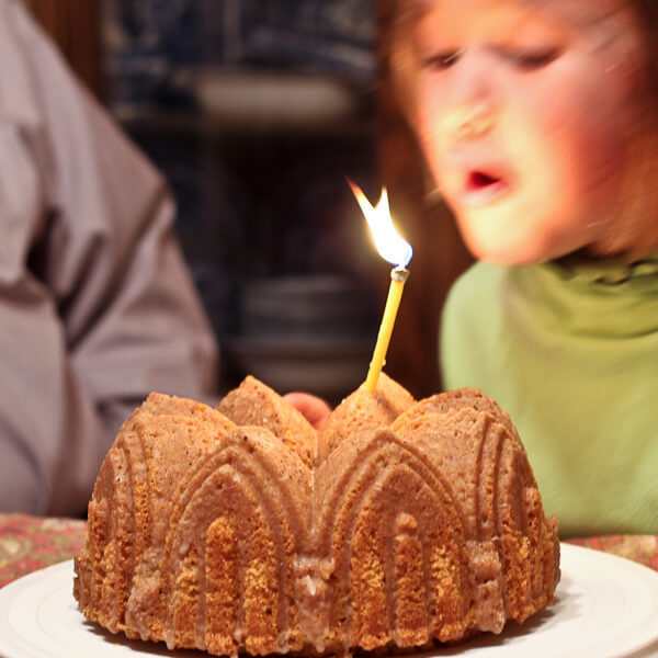 child blowing out candle on moroccan inspired birthday bundt cake